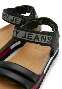 Sandali neri con doppie cinghie spesse, finitura in pelle texturizzata, cinghia in tessuto grigio con l'etichetta "MY JEANS", sottopiede in sughero naturale e suola multicolore.