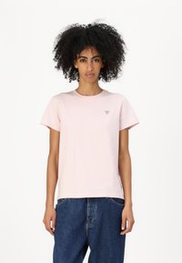 Tricou de bumbac roz, cu guler rotund și mâneci scurte. Prezintă un mic logo triangular pe piept și are o croială lejeră. Blugi din denim albastru.
