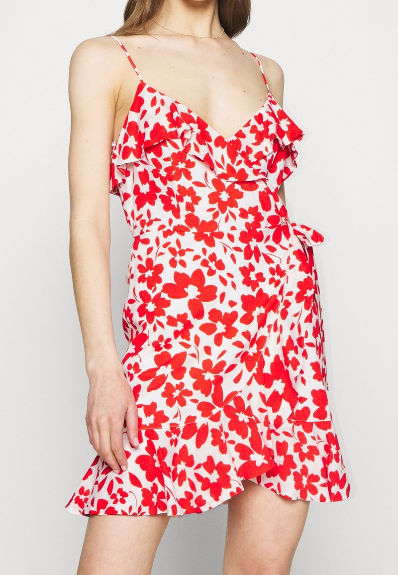 Blumenwickelkleid mit rot-weißen Mustern, V-Ausschnitt, Rüschendetails und einem ausgestellten Saum. Verfügt über dünne Träger und einen Taillengürtel.