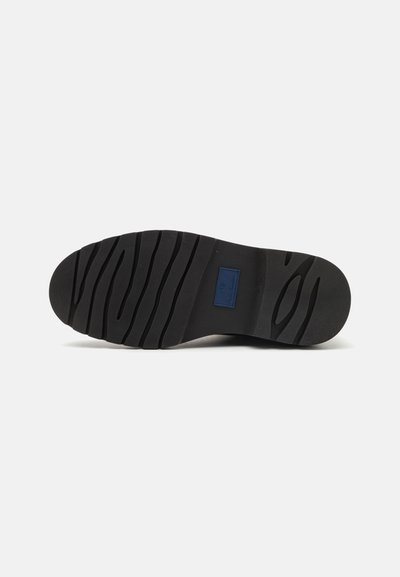Black rubber shoe sole with deep treads and a smooth layer. Features a rectangular blue brand logo near the heel area.