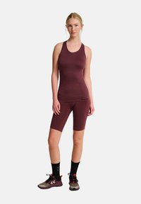 Burgunderfarbener sportlicher Body mit engem Schnitt, kombiniert mit passenden Shorts und schwarzen Socken, ergänzt durch mehrfarbige Sneaker.