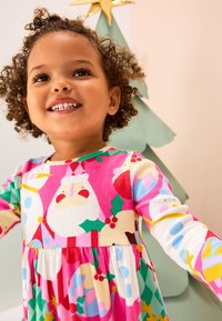 Vestido de manga larga con un estampado navideño colorido con Papá Noel, muñecos de nieve y acebo. La tela tiene una textura suave y acanalada.