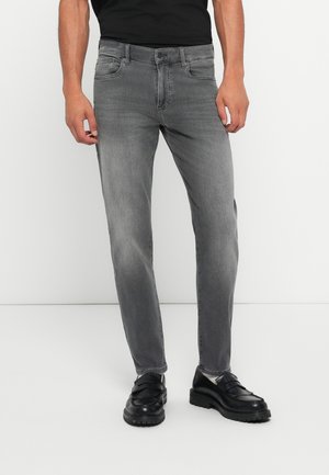 Slim-fit, gray denim jeans with a faded finish, five-pocket design, and waistband with belt loops. Paired with black loafers.