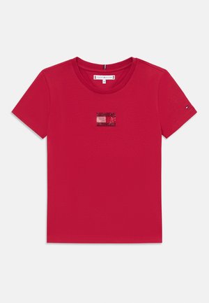 Tricou roșu din bumbac, cu mâneci scurte și gât rotund. Are un detaliu mic, strălucitor al logo-ului în centru. Textură netedă.