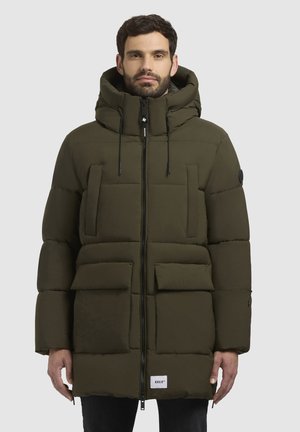Chaqueta de plumas color verde oliva con cierre de cremallera, grandes bolsillos frontales y capucha. Presenta una textura suave y detalles de costura visibles.