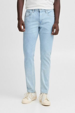 Ljust blå denimjeans med slim fit, med framfickor och en klassisk femficksdesign. Bärs med vita sneakers.