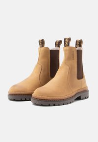 Bottines en cuir tan avec des panneaux latéraux en élastique et des tirants de marque. Semelle en caoutchouc robuste avec un profil texturé pour une meilleure adhérence.