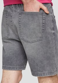 Szare szorty dżinsowe z wyblakłym wykończeniem, z dwiema tylnymi kieszeniami i podwiniętym dołem, zaprojektowane z elastycznym pasem dla wygody.