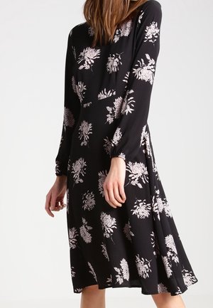 Abito lungo nero a maniche lunghe realizzato in tessuto leggero con una silhouette fluida. Presenta motivi floreali rosa e una leggerissima forma ad A.