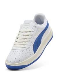 Weiße Ledersneaker mit einem blauen Wildlederstreifen, perforierter Zehenpartie, cremefarbener Zwischensohle und weißen Schnürsenkeln, sowie einer strukturierten blauen Außensohle.