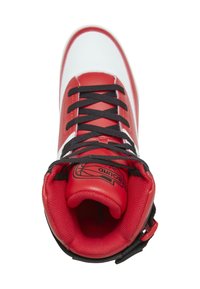 Baskets montantes rouges et blanches avec des lacets noirs. Tige en cuir lisse, col rembourré et languette texturée avec un logo de basket-ball.