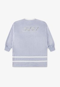 Velveta svijetloplava oversized košulja, s bijelim okruglim izrezom, dugim rukavima, srebrnim logotipom 23 na leđima i bijelim prugama na rubu.