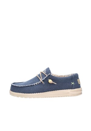 Blue canvas shoe with beige sole, contrasting stitching, and decorative toggle detail. Features a textured material and patterned inner lining.