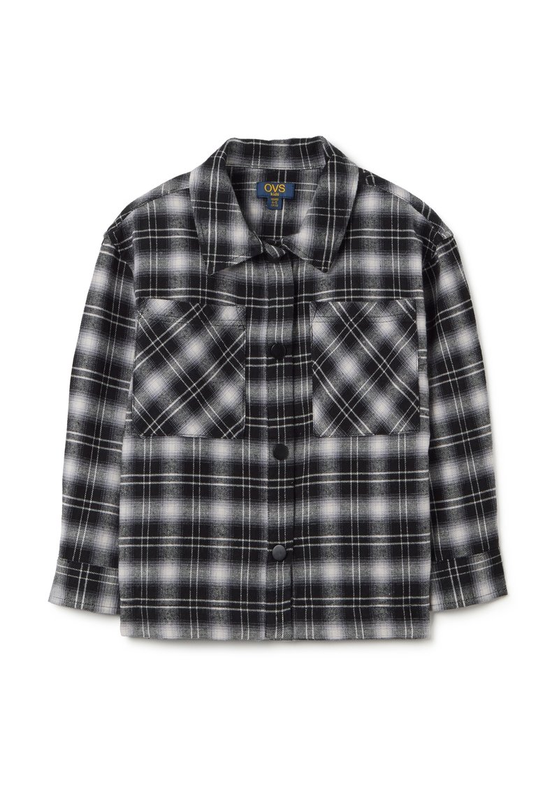 Camicia di flanella a quadri bianco e nero con due tasche sul petto, chiusura con bottoni e maniche lunghe, realizzata in un morbido tessuto texturizzato.