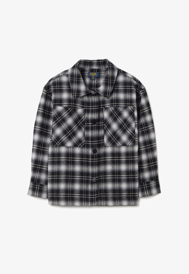 Camicia di flanella a quadri bianco e nero con due tasche sul petto, chiusura con bottoni e maniche lunghe, realizzata in un morbido tessuto texturizzato.