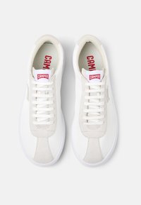 Sneaker bianche con dettagli in suede, lacci piatti e logo rosso "Camper" sulla linguetta. Finitura in pelle liscia e design della punta arrotondata.
