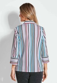 Gestreepte blouse met lange mouwen, gekenmerkt door verticale strepen in kleuren zoals bordeauxrood, blauw en wit. Opvallende manchetdetails op de mouwen.