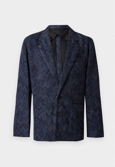 Blazer bleu foncé avec un motif zigzag subtil, deux boutons noirs, des revers crantés et des poches plaquées, présenté sur un fond clair uni.
