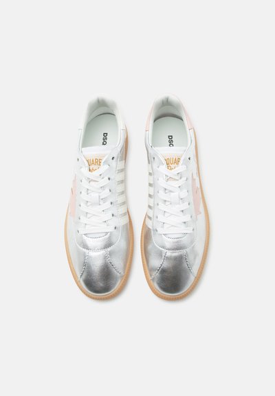 Paire de baskets basses blanches et argentées avec semelles en gomme et lacets, vues de dessus sur fond blanc.