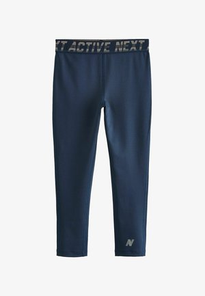 Leggings attivi blu marina con una ampia vita stampata che presenta la scritta "NEXT ACTIVE." Texture liscia, design aderente e piccolo logo alla caviglia.