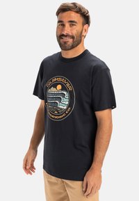Black cotton t-shirt with short sleeves and a crew neck. Features a circular graphic design with waves and a sun in vibrant colors.