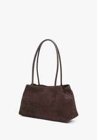 Brown suede tote bag with two long, smooth handles. Rounded shape with a soft texture and minimalistic design. No visible hardware or accents.