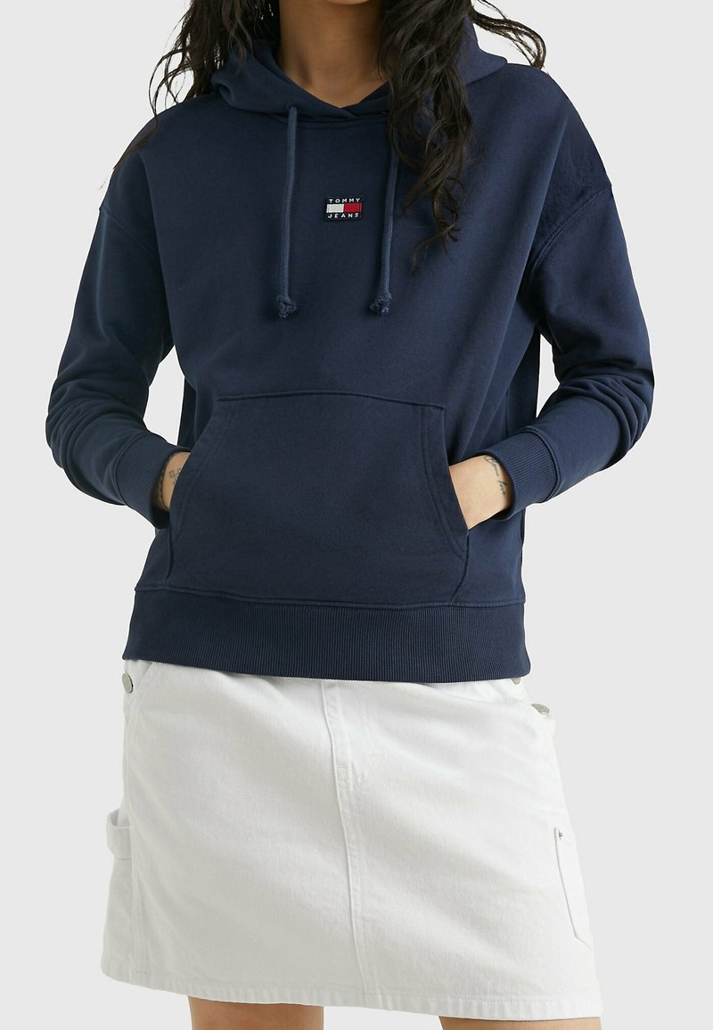 Felpa con cappuccio blu navy, in misto cotone, presenta una tasca frontale, dettagli con cordino e una piccola patch con logo sul petto.