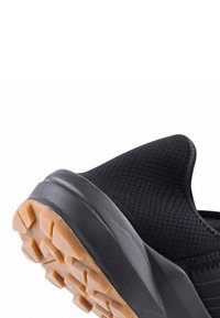 Scarpa atletica nera con parte superiore decorata, forma arrotondata e suola in gomma resistente con battistrada a nido d'ape.