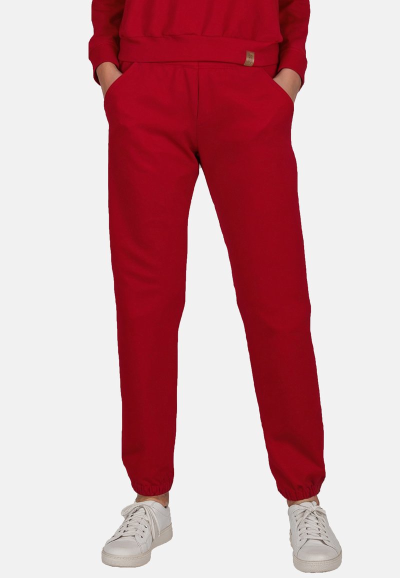 Rode sweatpants met een elastische tailleband, zijzakken en taps toelopende boorden, gecombineerd met witte sneakers. Gladde stofstructuur, casual ontwerp.