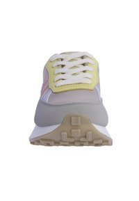 Zapatilla deportiva con un cuerpo gris y blanco, acentos en amarillo y rosa, un exterior texturizado y un frente con cordones. Suela gruesa de goma con un patrón.