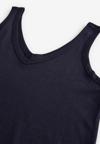 Mørkeblå ærmeløs tanktop lavet af bomuld, med en v-udskæring, subtil tekstur og pæne sømme langs kanterne.