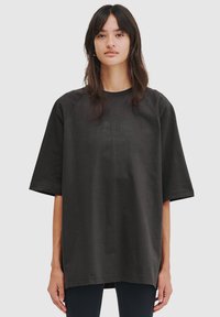 Overdimensioneret sort t-shirt lavet af blødt stof, med rund halsudskæring og korte raglanærmer. Inkluderer subtile grafiske detaljer foran.