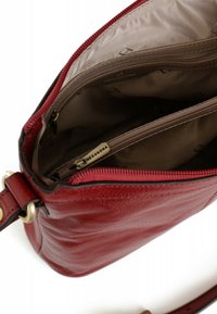 Borsa a tracolla in pelle rossa con superficie testurizzata, chiusura con zip superiore e interno beige dotato di tasca con zip e dettagli del logo.