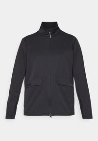 Czarna kurtka na zamek z wysokim kołnierzem, dwoma przednimi kieszeniami i teksturowaną tkaniną. Na dolnej lewej stronie znajduje się subtelne logo.