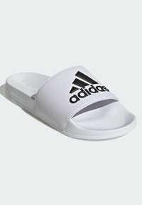 Ciabatte bianche con un cinturino testurizzato che presenta il logo Adidas in nero. La suola è bianca con una finitura liscia, progettata per il comfort.
