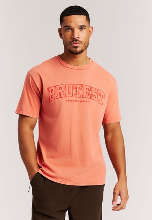 Koraalroze T-shirt met korte mouwen en het logo "PROTEST" in opvallend rood. Zachte, lichtgewicht stof met een ronde hals en een ontspannen pasvorm.