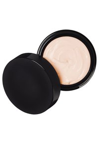 Pot circulaire noir avec un couvercle lisse, contenant une crème rose clair. La surface de la crème est légèrement tourbillonnée, indiquant une texture.