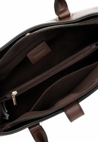 Interno di una borsa a tracolla in pelle nera con rivestimento in tessuto marrone, dotato di una tasca con zip, un'etichetta e molteplici scomparti per l'organizzazione.