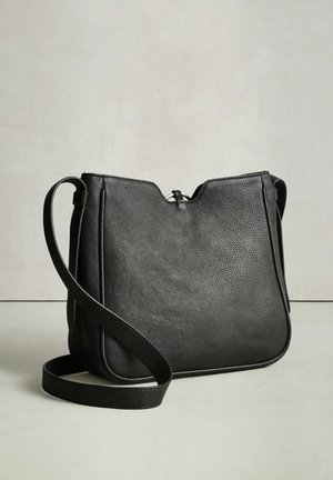 Melnās ādas soma pāri ķermenim ar gludu tekstūru, minimālistisku dizainu un vienu regulējamu siksnu. Aprīkota ar rāvējslēdzēja aizdari un mīkstām malām.