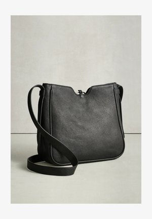 Musta nahkainen olkalaukku, jossa sileä pinta, minimalistinen muotoilu ja säädettävä olkahihna. Varustettu vetoketjulla ja pehmeillä reunoilla.