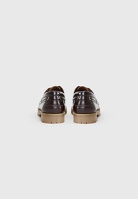 Brown leather shoes with a smooth finish, rounded shape, low rubber soles, and subtle stitching details. Features gold-tone hardware accents.