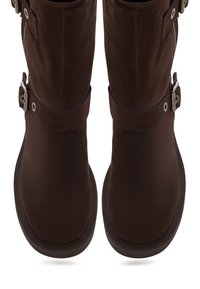 Cizme peste genunchi din piele întoarsă maro, cu textură netedă, vârf rotund și catarame metalice decorative la gleznă. Închidere cu fermoar pe lateral.