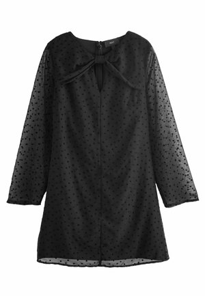 Robe noire à motifs à pois, manches longues transparentes et encolure ronde. Présente un détail en nœud et une fermeture éclair au dos.