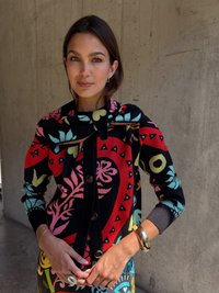 Pletený kardigán s odvážnym kvetinovým vzorom v červenej, čiernej a tyrkysovej farbe, s gombíkovým zapínaním a rebrovanými manžetami. Skombinovaný s dnom s mnohobarevným vzorom.