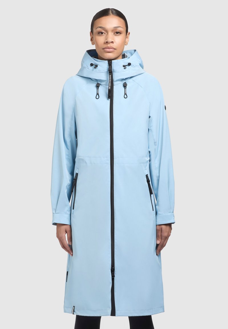 Giacca impermeabile blu chiaro con zip frontale completa, cappuccio regolabile e tasche con zip; texture liscia e vestibilità lunga e rilassata.