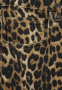 Denim tkanina s leopard uzorkom ima kombinaciju smeškastih i crnih uzoraka, s vidljivim stražnjim džepom i detaljnim šavovima.