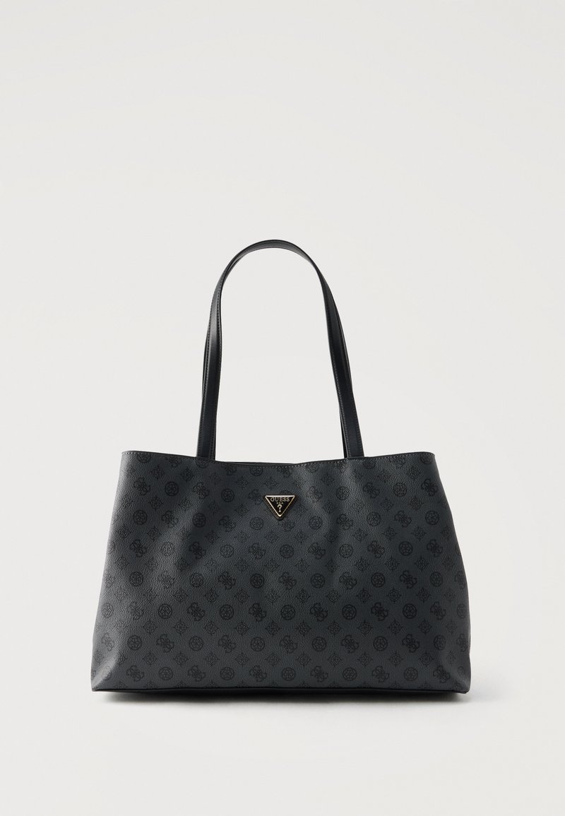 Μαύρη τσάντα tote με υφασμένο μοτίβο μονόγραμμα, δύο λεπτές λαβές και μια μικρή τριγωνική πλακέτα με το λογότυπο Guess στο κέντρο κοντά στην κορυφή.