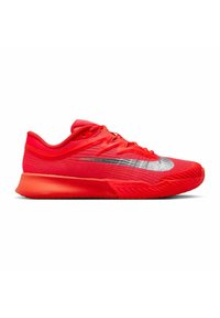 Helle rote Sportschuh mit silbernem Nike-Swoosh, Obermaterial aus Mesh, gepolsterter Sohle und Schnürverschluss, seitlich auf weißem Hintergrund präsentiert.