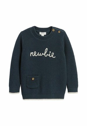 Marineblå strikket børnesweater med teksten "newbie", lomme foran med knap og to skulderknapper, hvid kant på ærmer og kant.