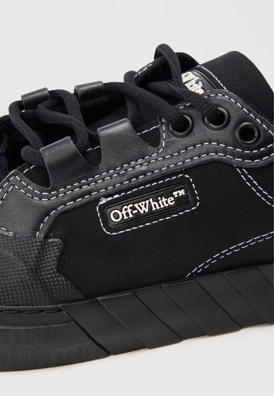Czarne sneakersy Off-White z teksturowaną podeszwą, białymi kontrastującymi przeszyciami, czarnymi sznurówkami przewleczonymi przez metalowe oczka oraz naszywką z logo.